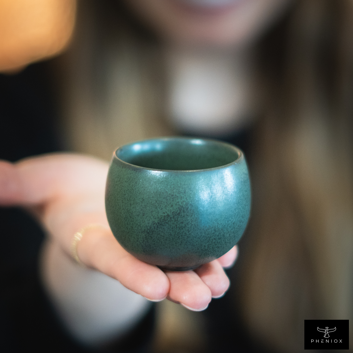 Frau präsentiert grüne Espressotasse in Nahaufnahme