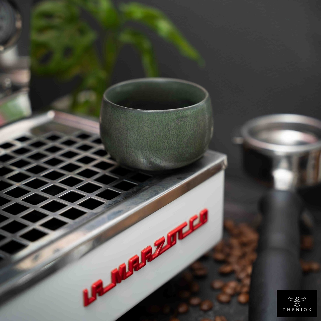 Grüne Espressotasse steht auf Siebträgermaschine mit Kaffeebohnen