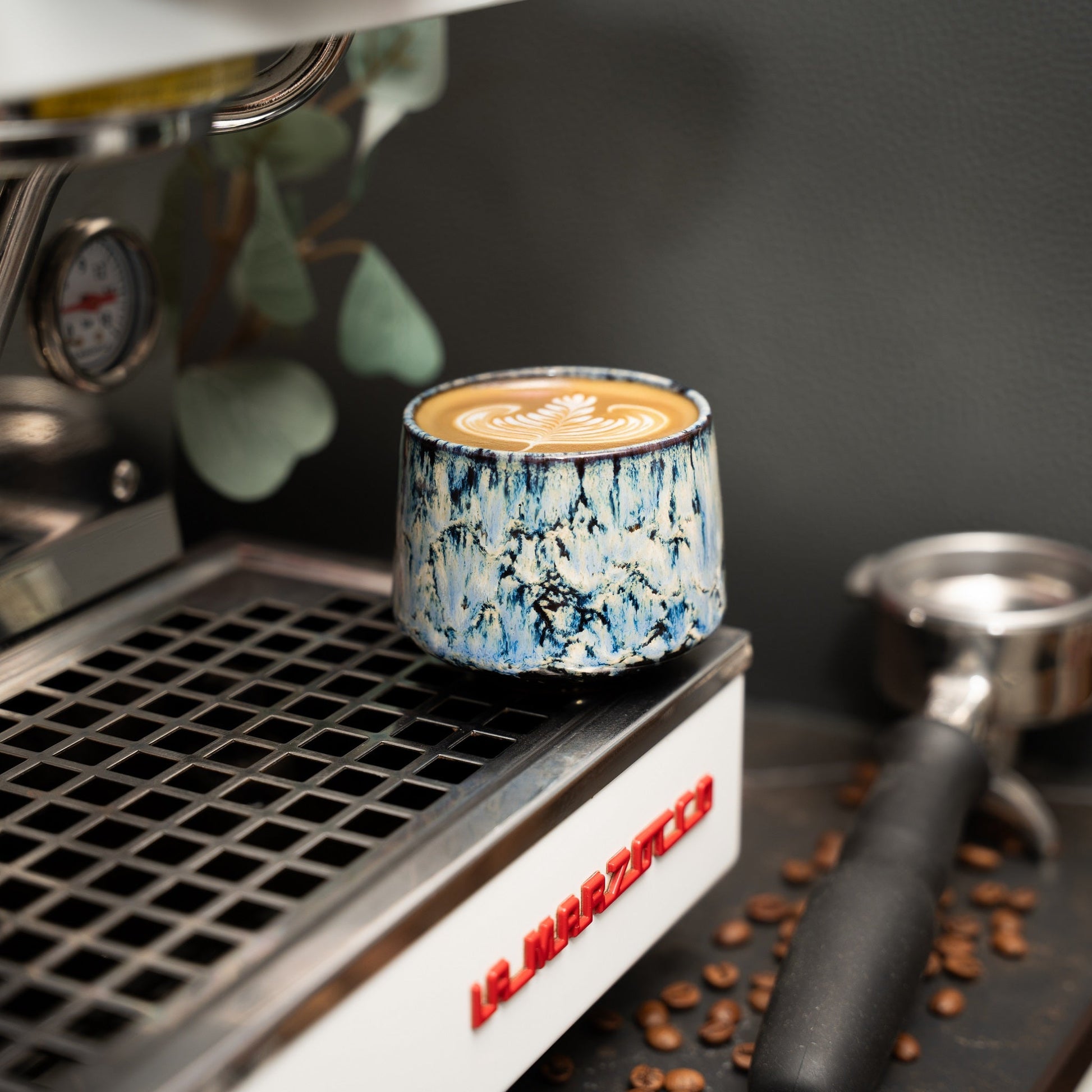 Cappuccino Tasse auf einer Siebträgermaschine mit Latte Art darin.